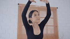 Asian young beautiful woman practice dancing ballet rehearsing at home. Attractive young girl ballet dancer spinning and jumping in a tutu and pointe shoes, doing stretching dance with yoga elements.