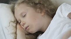 Beautiful curly hair blond child sleeping in her bed, healthy sleep, close-up