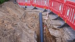 Pipe en PVC à gaz exposée au chantier de construction des routes Site protégé par une barrière de sécurité rouge temporaire