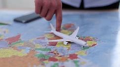 Woman travel agent plays with model airliner put on paper map of world axis with markings of different countries. Providing flight services from expert to client