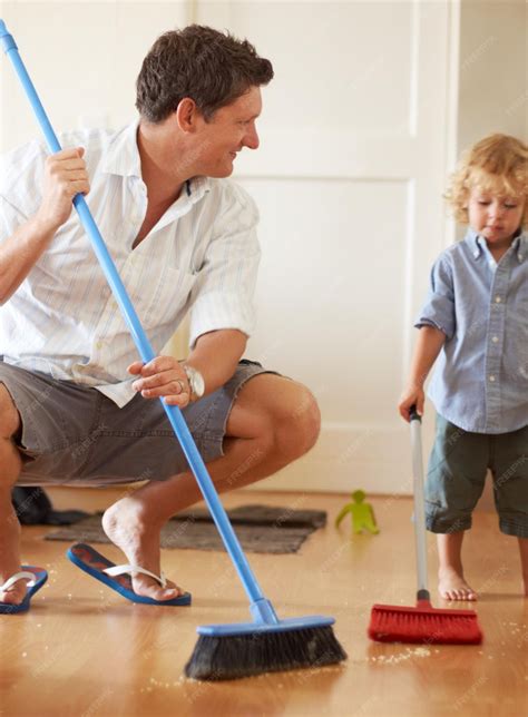 Premium Photo | Man is cleaning with boy child sweeping with broom and ...