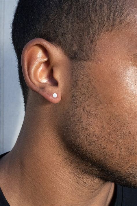a close up of a man with an ear piercing on his left side and the top ...