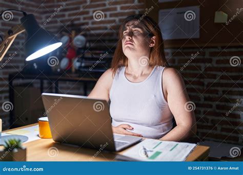 Brunette Woman Working at the Office at Night with Hand on Stomach ...
