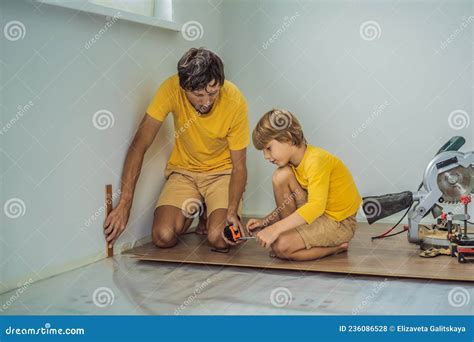 Father and Son Installing New Wooden Laminate Flooring on a Warm Film ...