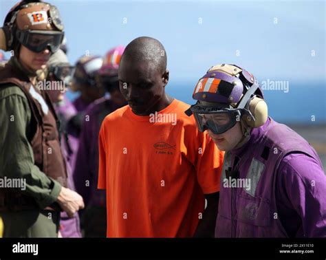A Navy flight deck crewmember escorts a Haitian earthquake victim into ...