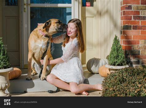 Dog licking a girl's face outside on the front porch stock photo - OFFSET