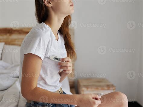 woman sitting on bed with thermometer armpit checking temperature 22310504 Stock Photo at Vecteezy