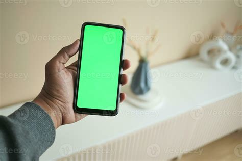 men holding a smart phone with green screen against home interior ...