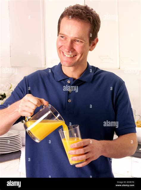 MAN IN KITCHEN POURING ORANGE JUICE Stock Photo - Alamy