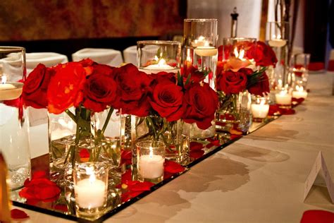 Romantic centrepiece of red roses and candle light sitting on top of a ...