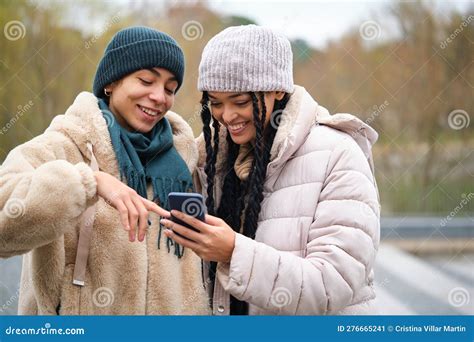 Happy Dominican Lesbian Couple Using the Phone at Street in Winter ...