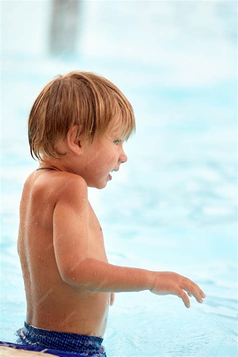Premium Photo | Little boy in blue swimming trunks learns to swim in ...