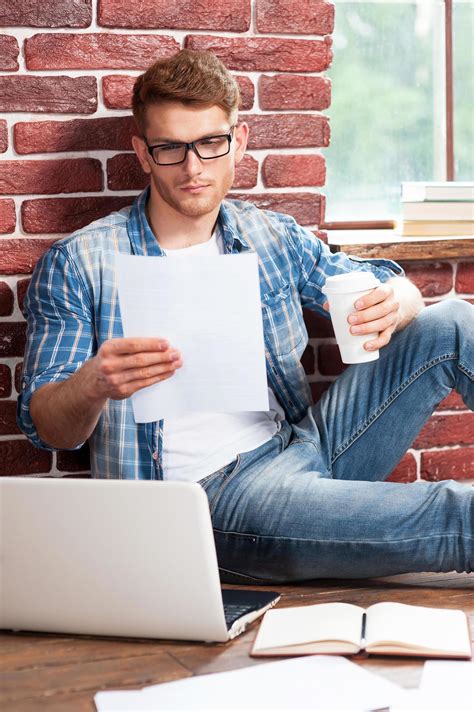 Doing some paperwork at home. Handsome young man sitting on the floor ...