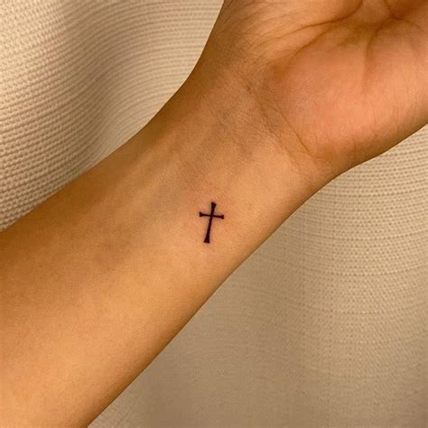 Minimalist cross tattoo on the wrist.