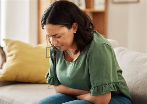 Stomach pain, stress and woman on a sofa with pms, gas or bloating ...