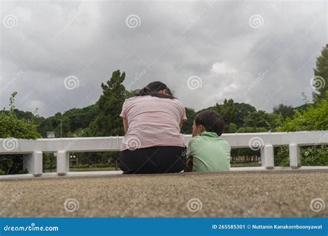 Back View of Loving Asian Mother Hug Her Kids Sitting on Bridge, Caring Black Mom Embrace Child ...