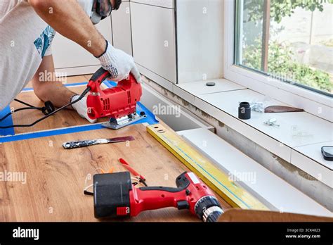 repairman using electric jigsaw and cutting hole for the sink in the ...