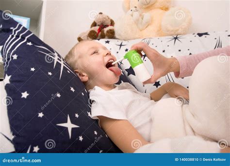 The Mother Treats the Baby, the Spray from a Sore Throat. Stock Photo ...