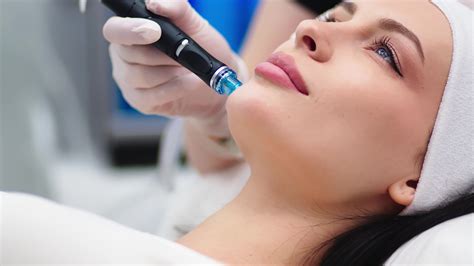 Professional dermatologist in medical gloves doing facial hydro peeling ...