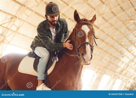 Sitting in the Saddle. Young Man with a Horse is in the Hangar Stock ...