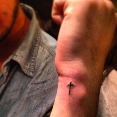Hand poked minimalistic cross tattoo located on the