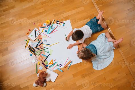 Kids drawing on floor on paper. Preschool boy and girl play on floor ...
