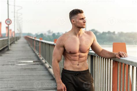 Muscular man with naked torso during fitness workout on a bridge ...