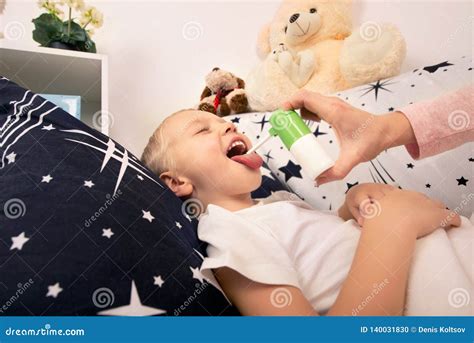 The Mother Treats the Baby, the Spray from a Sore Throat. Stock Photo ...