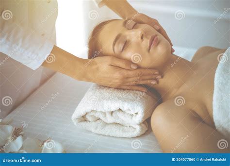 Beautiful Brunette Woman Enjoying Facial Massage with Closed Eyes in ...