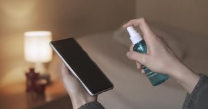 Woman Cleaning Sanitizing Disinfecting Cell Phone Against Virus Bacteria Germs