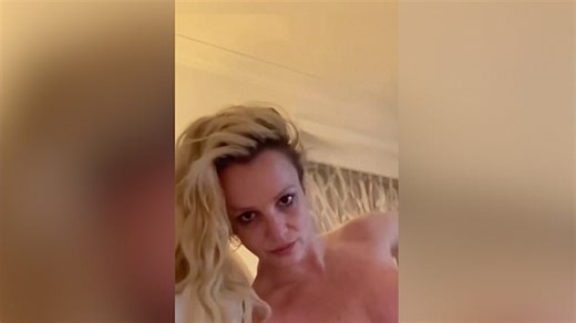 Britney Spears rolls around in bed topless in racy video