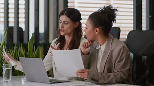 Multiethnic diverse girls ladies women business partners coworkers African American Caucasian female teamwork review documents using laptop analyze information corporate office smiling businesswomen