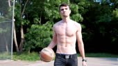 Young muscular man playing basketball in the park