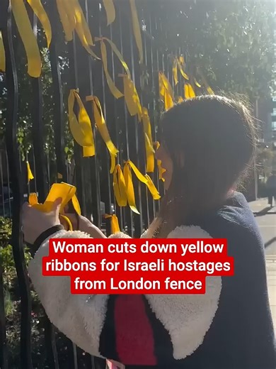 Woman cuts down yellow ribbons for Israeli hostages from London fence