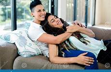 embracing relaxing sofa smiling lesbian couple preview