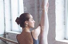 stretching ballet leg dancer young female studio ballerina active lifestyle serious practice window looking