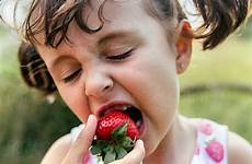 girl eating little strawberries stocksy united