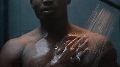 African American sexy naked guy washing with lotion gel apply shampoo bottle in dark shower bathroom athletic bare wet man cleaning muscular body liquid soap foam hot water male beauty bath cosmetics