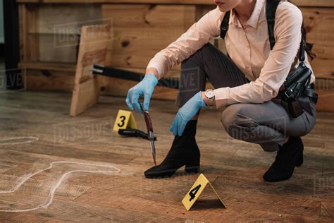 Cropped view of female detective collecting evidence at crime scene ...