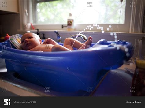 When the lesson is over, fill 'em up for a playful water fight! A baby boy urinates during a bath stock photo - OFFSET