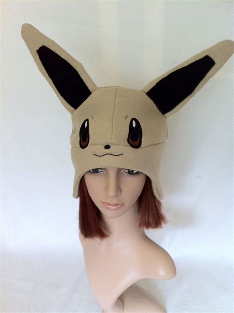 This hat is made with acrylic yarn and features a pokeball themed bow. Pokemon Evee Fleece Earflap Beanie | Pokemon hat, Pokemon ...