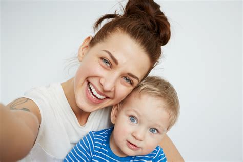 Mother and son bedroom scene. Young mother with her one years old little son dressed in ...