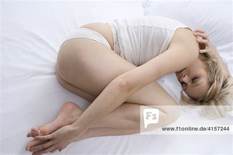 Harter fick auf dem bett. Blonde Frau in Unterwäsche liegt zusammengerollt im Bett ...