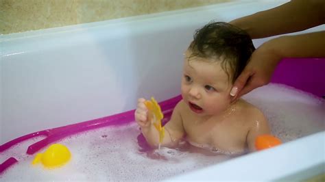 Baby sloth bath time = cute crack. Cute toddler girl taking a bubble bath. Close-up of mom's ...