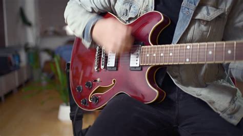 Electric guitars, esp bass guitars, can be heavy and are more easily supported by a strap while standing. man sitting down and playing a red electric guitar by ...