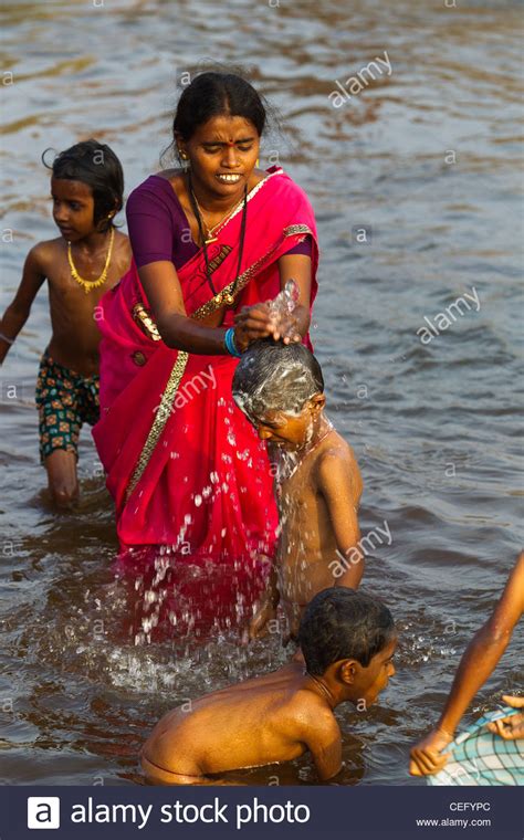 To use as a daily bath powder: Indian mother bathing his son on the waters of Tungabhadra ...