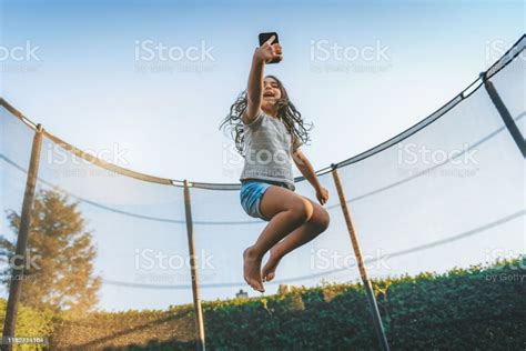 Yes, jumping on a trampoline exercises the whole body. Little Girl Jumping High On Trampoline With Mobile Stock Photo - Download Image Now - iStock