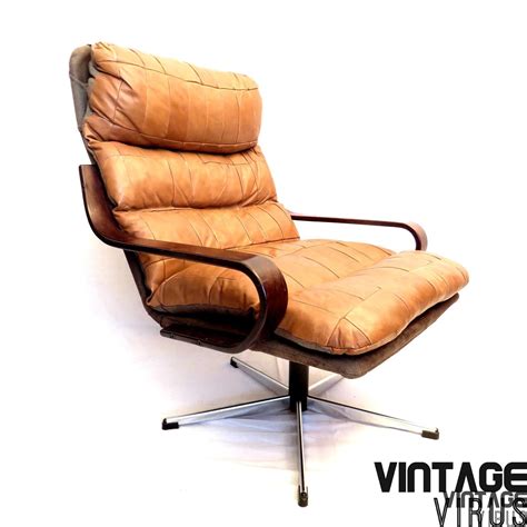 De stoel en krantenbak zijn waarschijnlijk deens. Deense vintage design patchwork cognac leren fauteuil