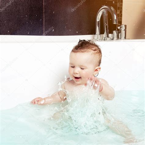 In many families, a bath becomes the focus of a nightly bedtime routine. Cute baby having fun, splashing water and laughing while ...