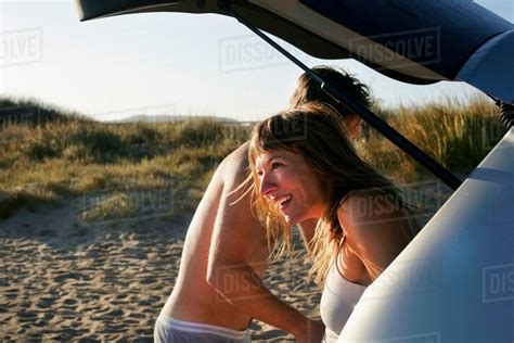 Mid adult couple changing clothes from car on beach - Stock Photo ...